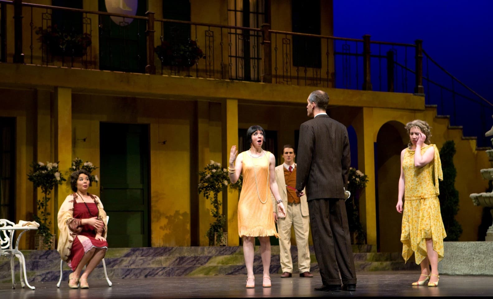 a man has his back to the audience, and Sarah, whose face is to the audience, is singing to him. Other characters on stage
                            look distressed.
