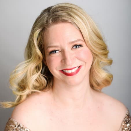 Sarah Iles wearing a golden sequins dress and smiling at the camera while sitting.
